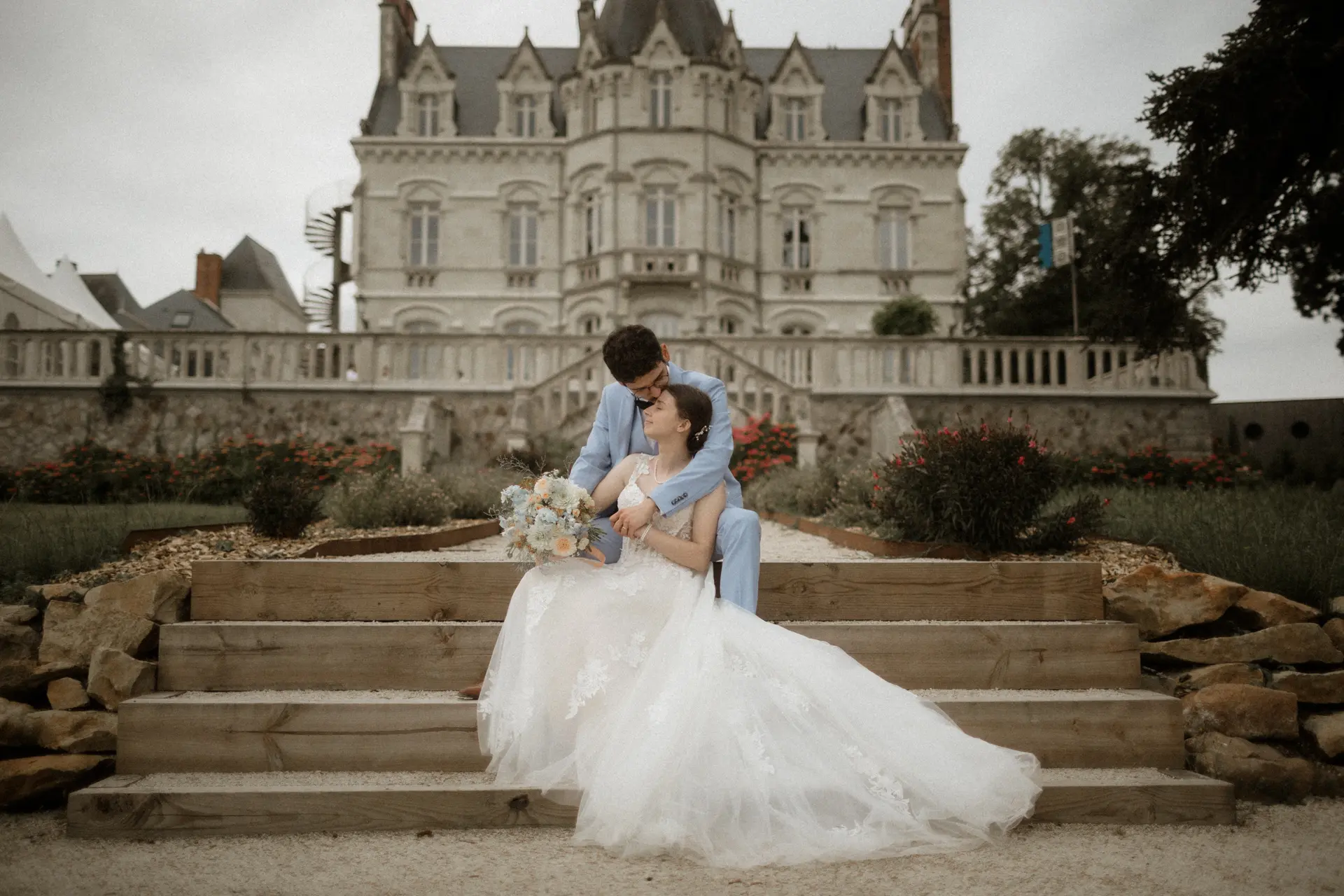 Bride and groom sitting on the steps of a romantic French château during their destination wedding in the Loire Valley