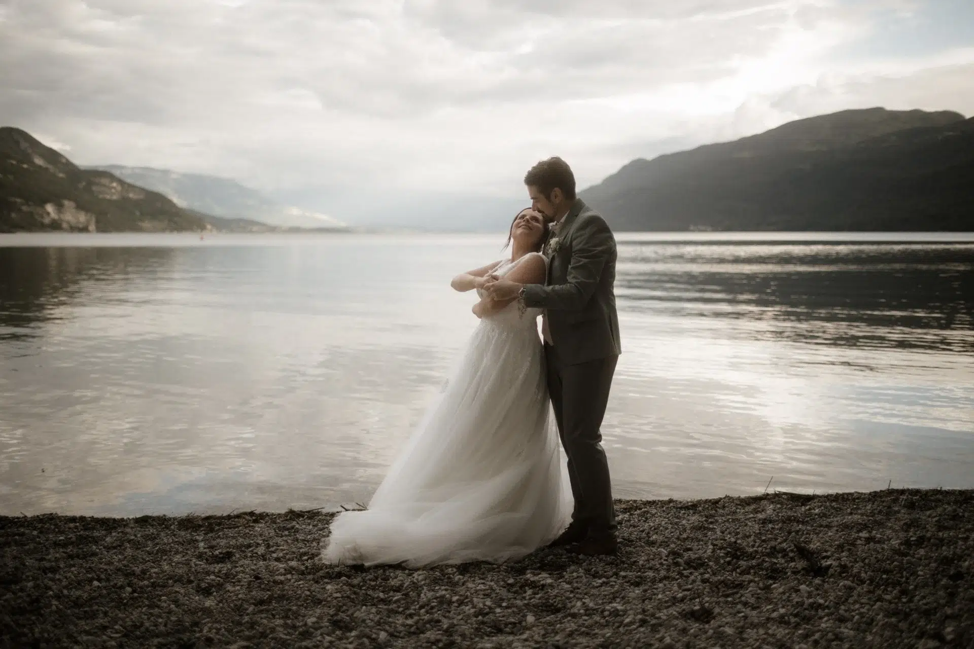 Océane et Stéphane enlacés au bord du lac du Bourget à Chindrieux, avec les montagnes en arrière-plan.